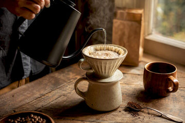 Hand pouring water over light roast coffee grounds